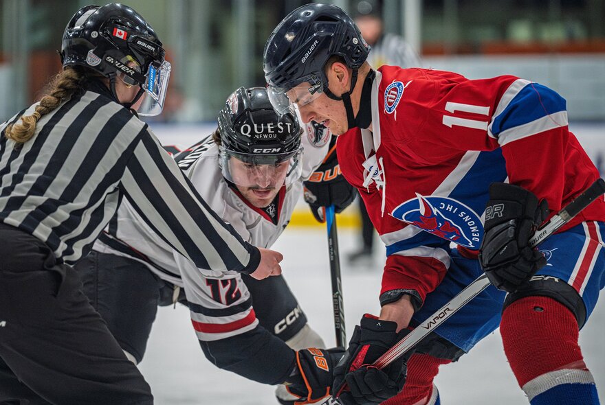 Three ice hockey players on the ice during a game.