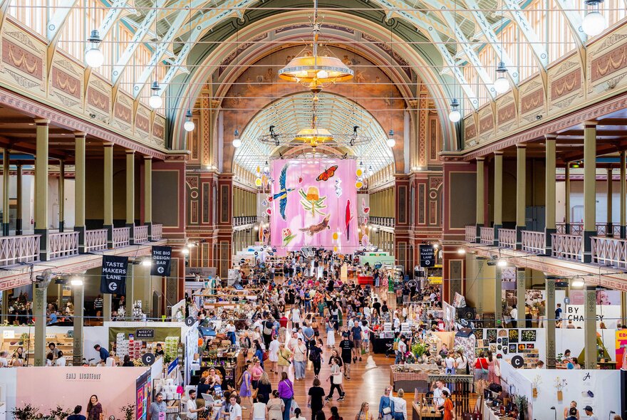 Large crowds of people browsing designer stalls and food carts at the Big Design Market inside the Royal Exhibition Buildings.