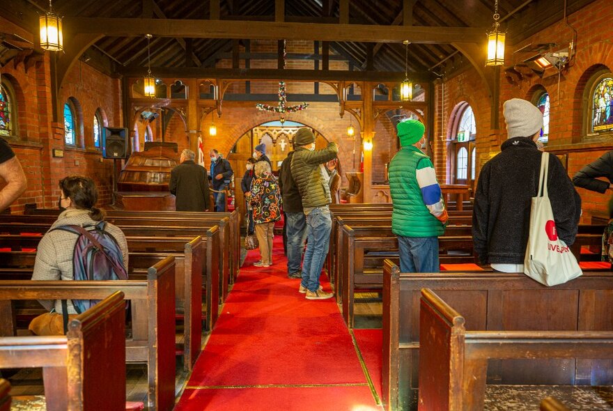 People exploring an old church-like building with red carpet. 