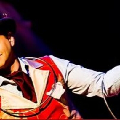 Performer wearing a hat and waistcoat, with rope.