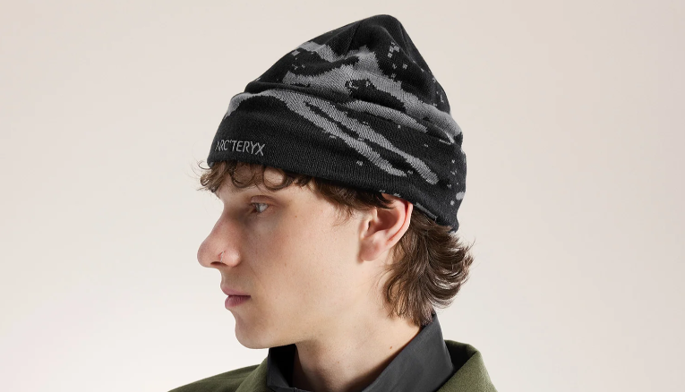 A model wearing a black beanie with grey abstract print.