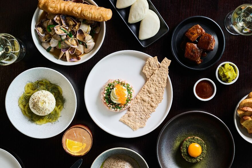 Looking down on a table with many plates of food, large and small.