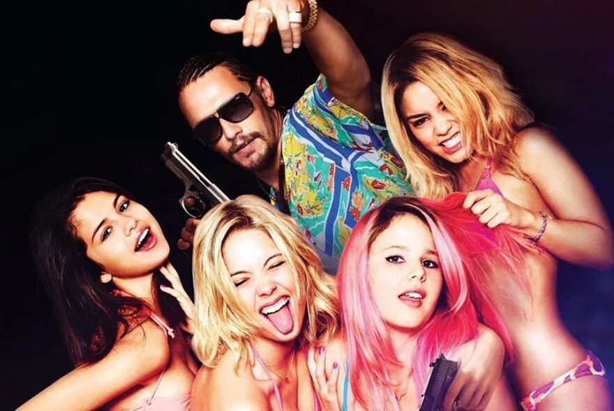 Four young women and a man wearing sunglasses and acting like they're in a rap video.