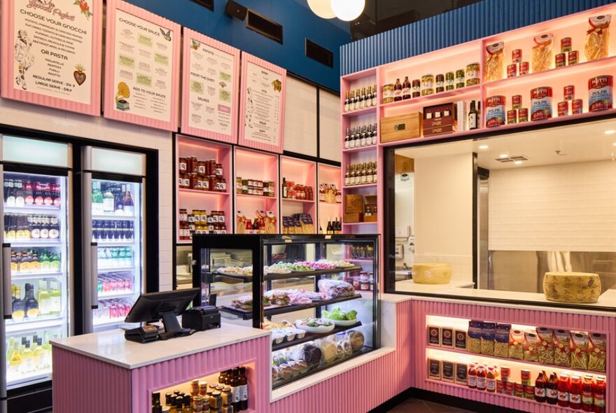 Takeaway store with pink counter, display cabinet and shelves, and pink menu signs.