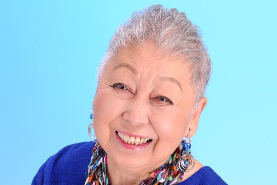 Smiling older Japanese lady with eyebrows raised.