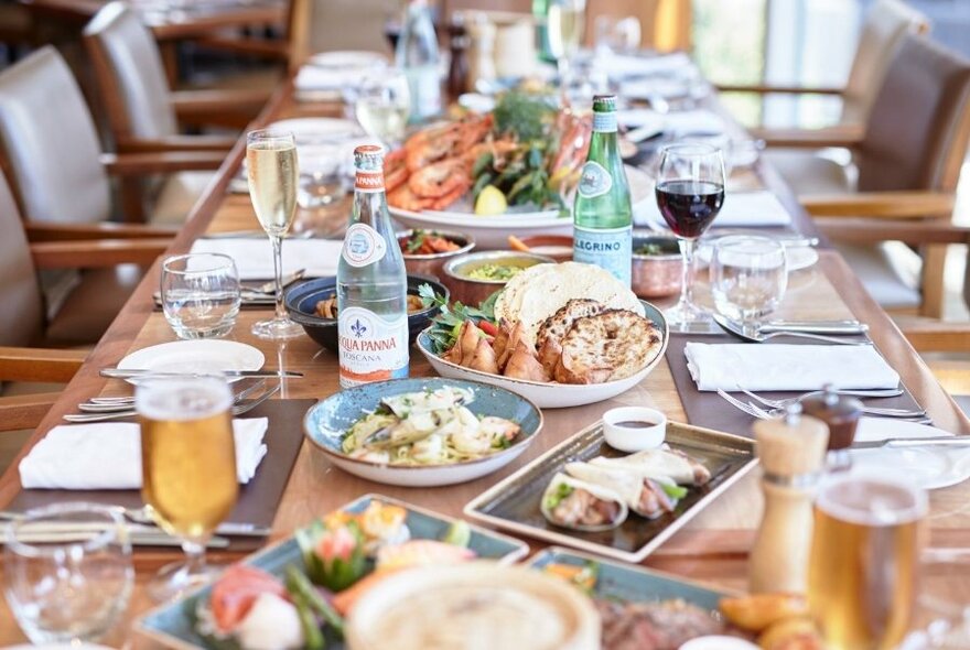 Long restaurant table with plates of food.