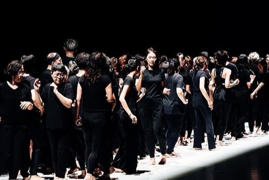 Older people wearing black outfits, standing in a group.