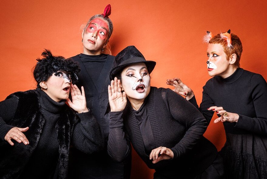 Actors wearing black gowns and face make-up in the characters of rooster, fox, cat and bird.