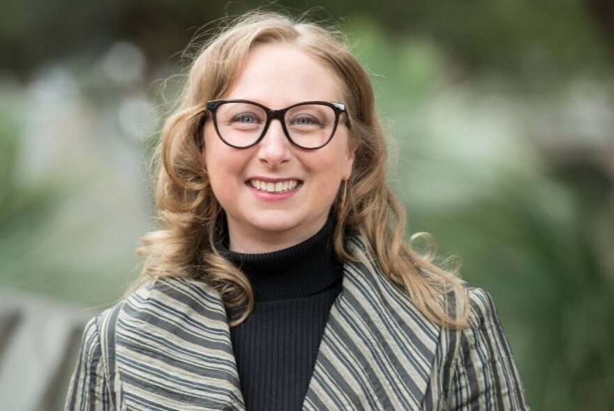 Portrait of Professor Michelle D. Lazarus, smiling, in front of a blurred green background.