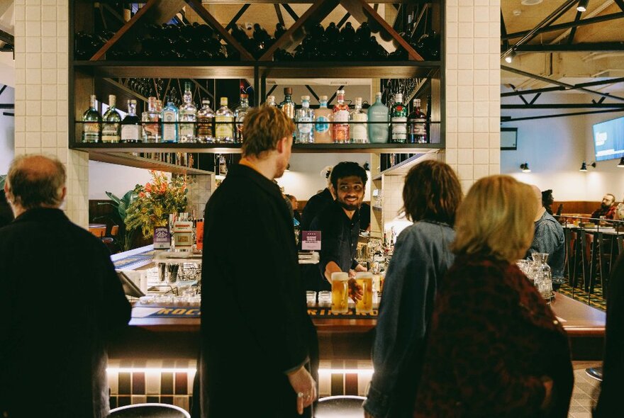 People standing around waiting to be served at a bar.