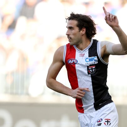 A St Kilda AFL player running on the field with one hand raised above with finger pointing in a victory gesture.