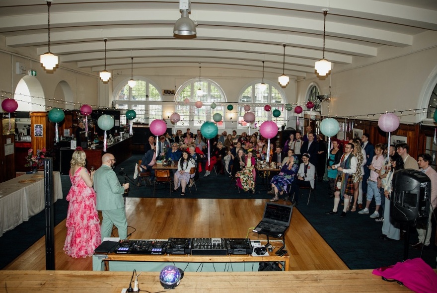 Inside an old building in a large event space with balloons and lots of people.