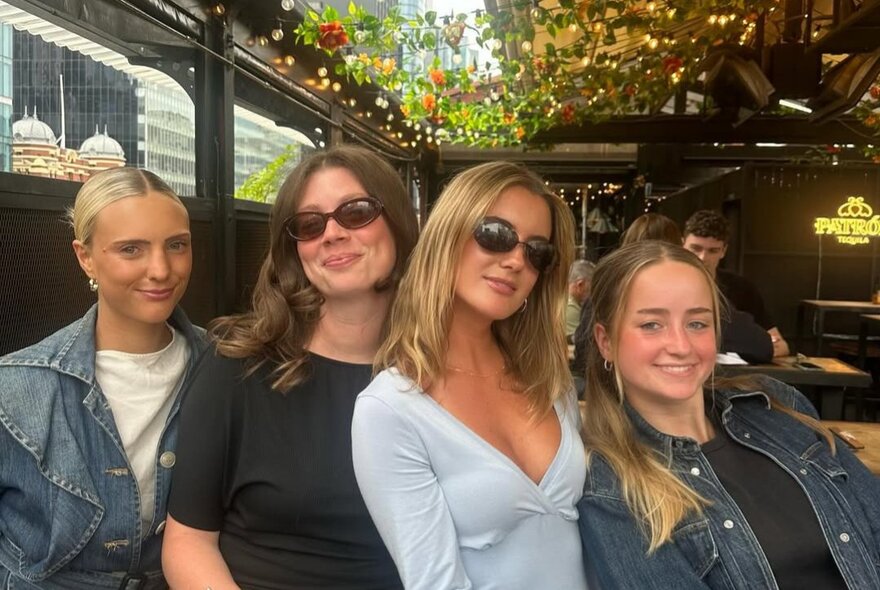 Four women posing for a group shot in a outdoor bar setting. 
