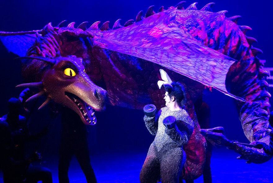 The dragon and the donkey characters from Shrek The Musical interacting on a theatre stage.