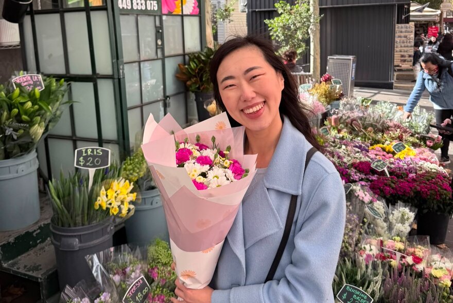 Smiling woman holding a bunch of flowers at a florist.