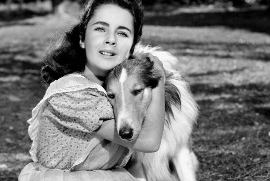 A still from the motion picture Lassie with a young girl hugging her dog.