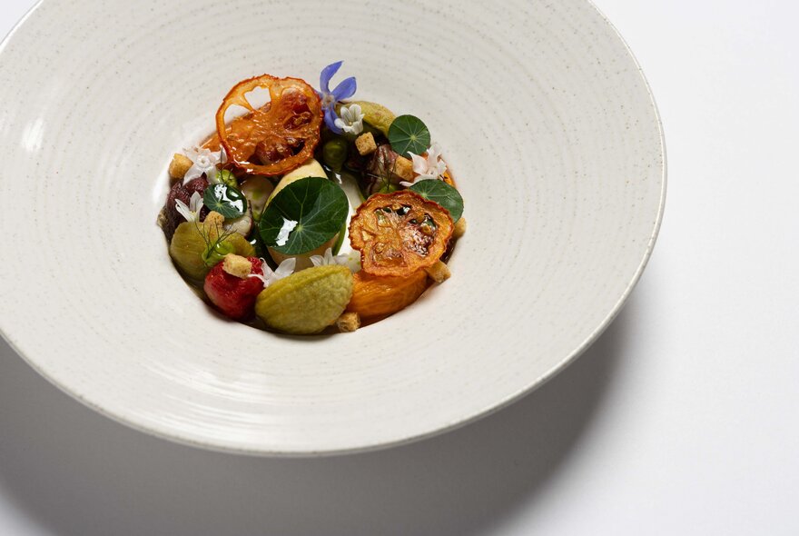 A large white bowl with a small circle of tomatoes and herbs in the centre. 