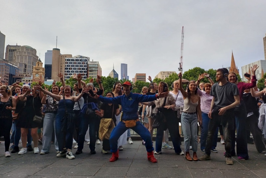 Group of disco walking tour participants dancing i the street with city buildings in the background.