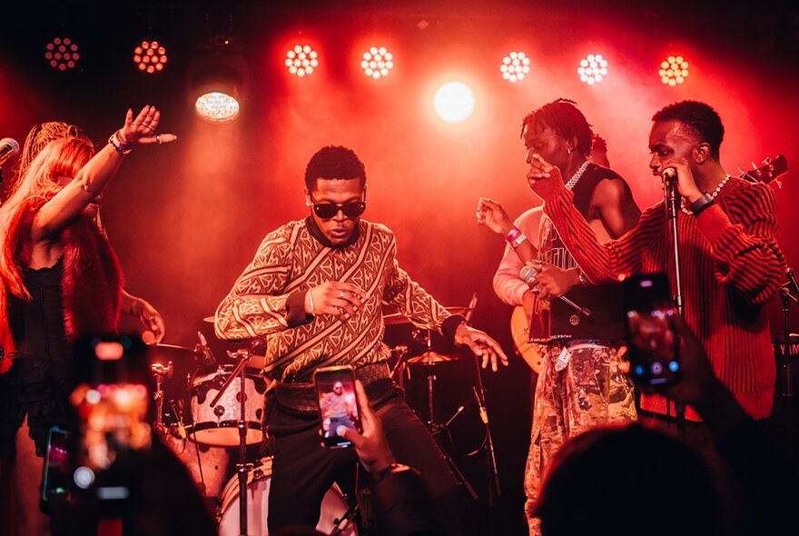 Musicians performing under red lights.