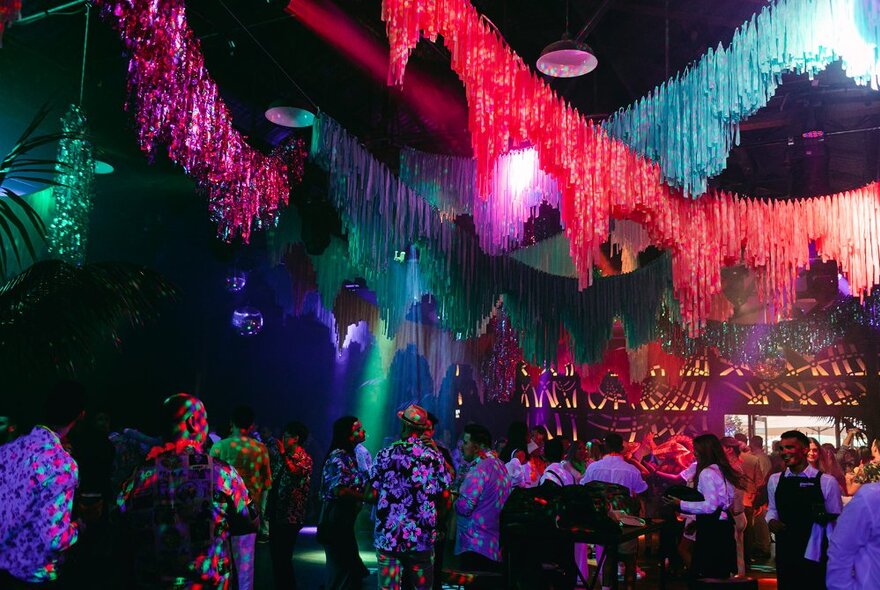 A dimly lit nightclub with coloured garlands across the ceiling.