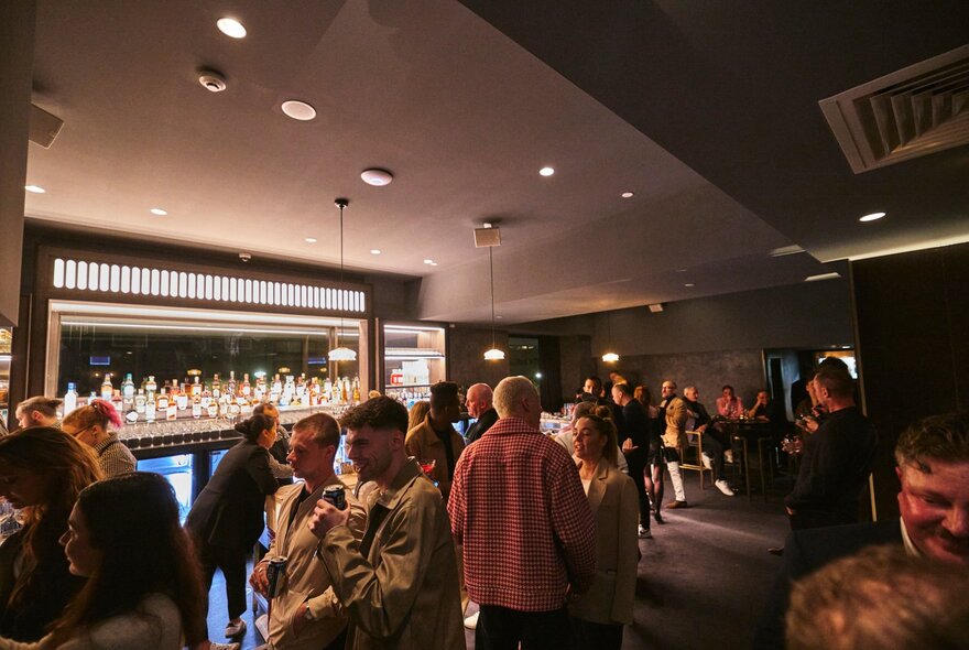 The cocktail lounge area at Blackbird with people standing around socialising and drinking in front of the bar area.
