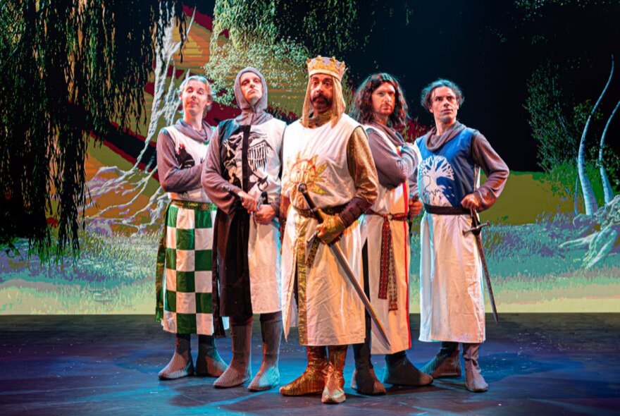 King Arthur and knights standing on stage in medieval dress.