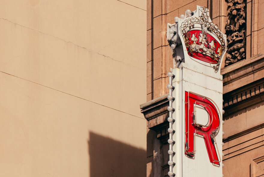 Close-up of the vintage sign for the Regent Theatre in Melbourne, featuring a red 'R' and a crown logo.