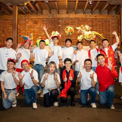 The True Colours male choir wearing white t-shirts and jeans, posing informally with hands raised in friendly gestures.