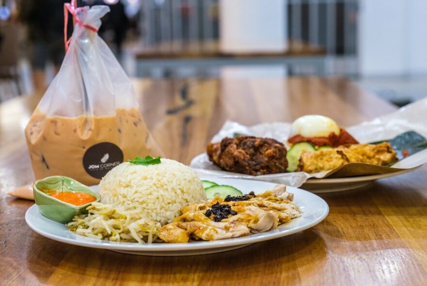 Dome of rice and chicken on a wooden table with an iced coffee in a plastic bag.