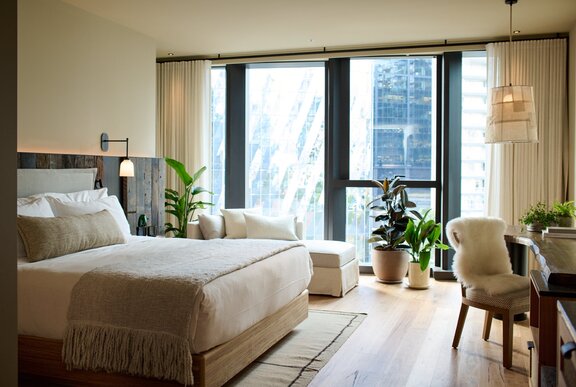 A hotel room with a rustic interior design and a large floor-to-ceiling window.