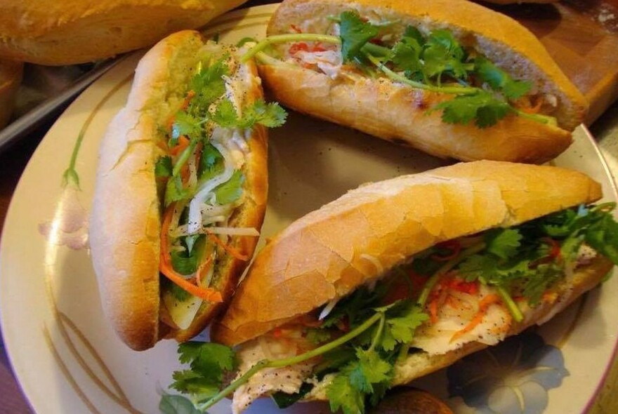 Three banh mi making a circle on a plate.