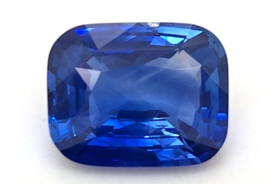A blue sapphire gemstone cut into a cushion shape.