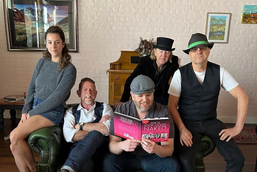 Five-piece Irish band of musicians seated on a chesterfield sofa wearing hats.