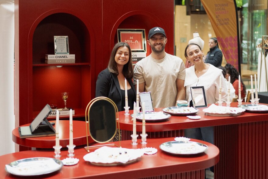 A sleek, red-themed market setup with arched displays and candles from Melbourne Fashion Week at Collins Square.