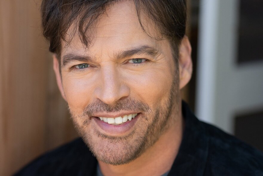 Jazz musician Harry Conick Jr, with stubble and white teeth.