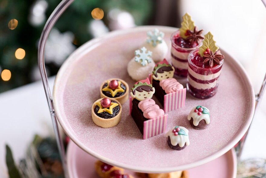 Selection of star-shaped and festive cakes on a pink tiered cake stand.