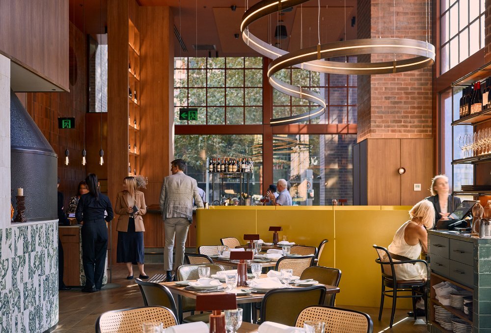 A bright restaurant with high ceilings and a winding light installation.