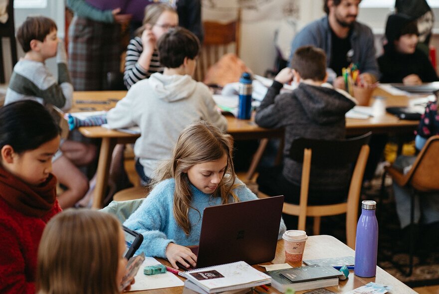 Children seated at tables with laptops.