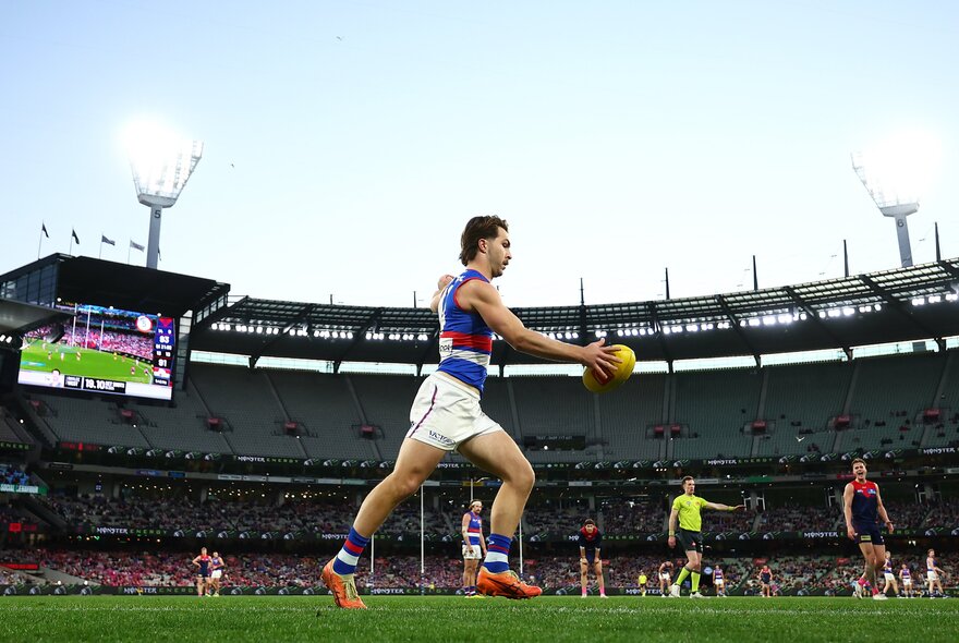 A Western Bulldogs football player lines up to kick during a match. 
