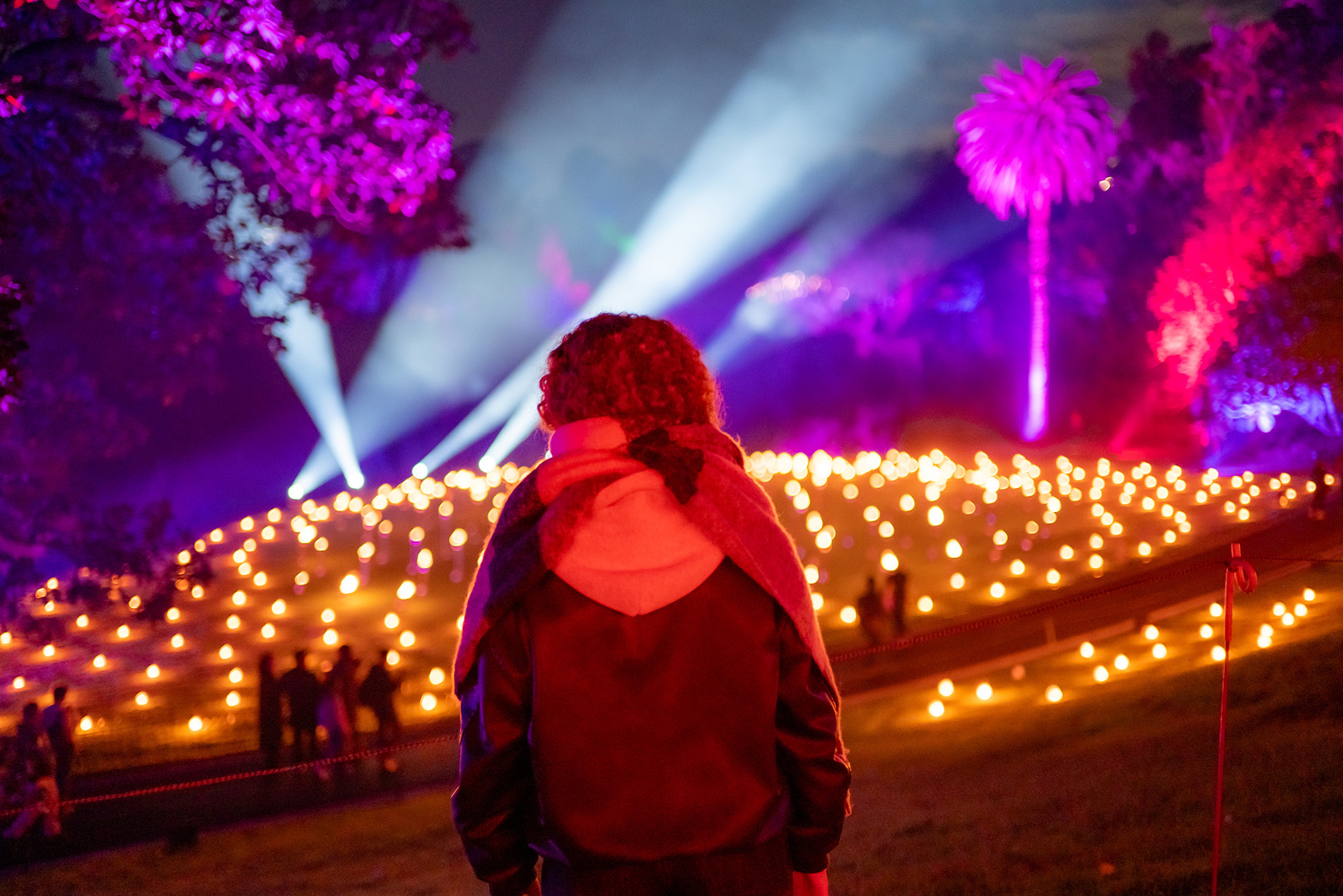 A girl looking at a light display in a garden at night.