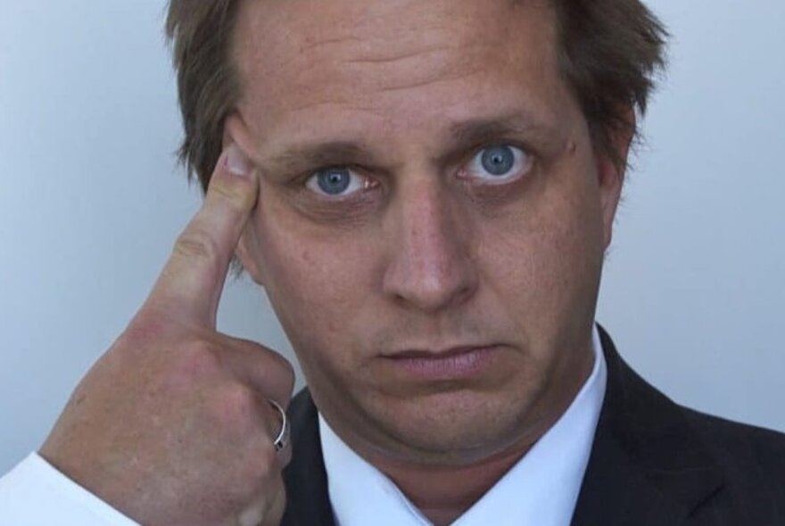 A man looking frazzled with his head resting on a single finger. 