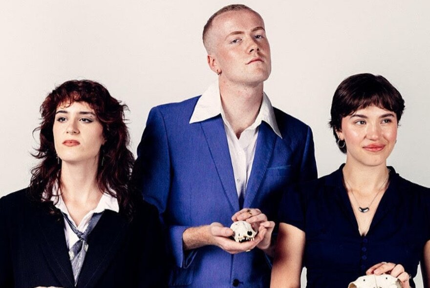 Three performers, one man and two women, holding skulls.