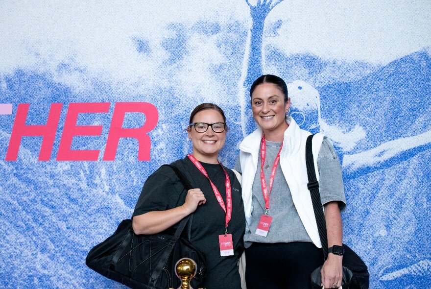 Two people in front of a fitness poster wearing lanyards around their necks. 