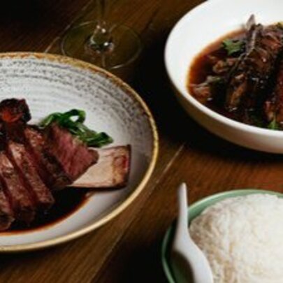 A plate of beef short ribs and lamb and a bowl of rice.