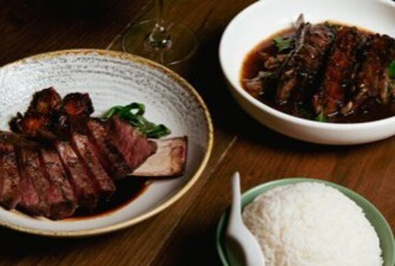 A plate of beef short ribs and lamb and a bowl of rice.