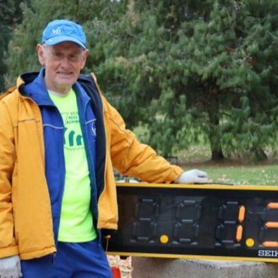 Man wearing bright jackets and cap next to a large digital timer.