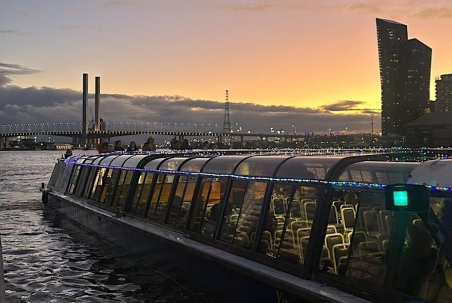 A sightseeing boat on the harbour against a twilight background.