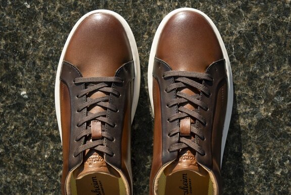 Looking down at a pair of men's brown leather lace up casual shoes.