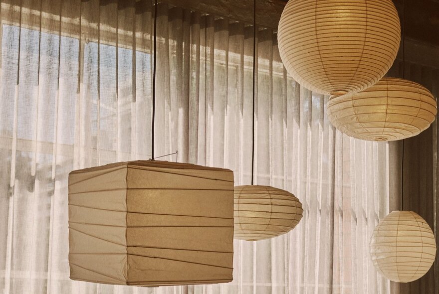 Japanese paper lantern lights suspended next to transparent curtains.