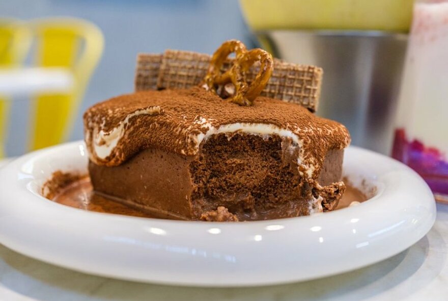 A slab of tiramisu with a pretzel on top.